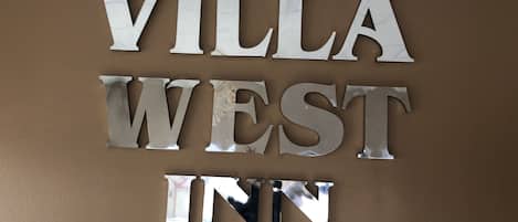 Un letrero con el texto 'VILLA WEST INN' en una pared marrón.