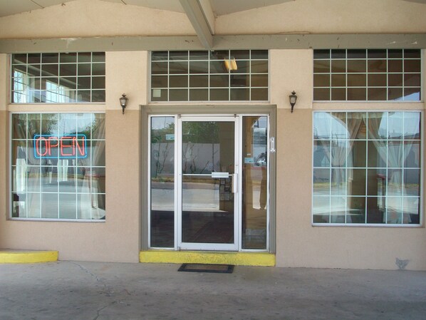 A building facade with a large glass door entrance, a neon 'OPEN' sign, and a yellow curb.