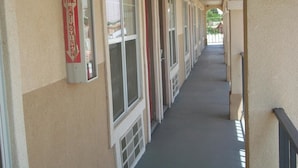 A corridor with fire extinguishers on the wall, windows, and a covered walkway. - Villa West Inn (Odessa)
