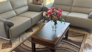 A living room with a sofa, a coffee table, and a vase of flowers. - Villa West Inn (Odessa)