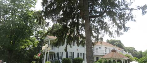 A large white house with a porch, a gazebo, and a white picket fence.