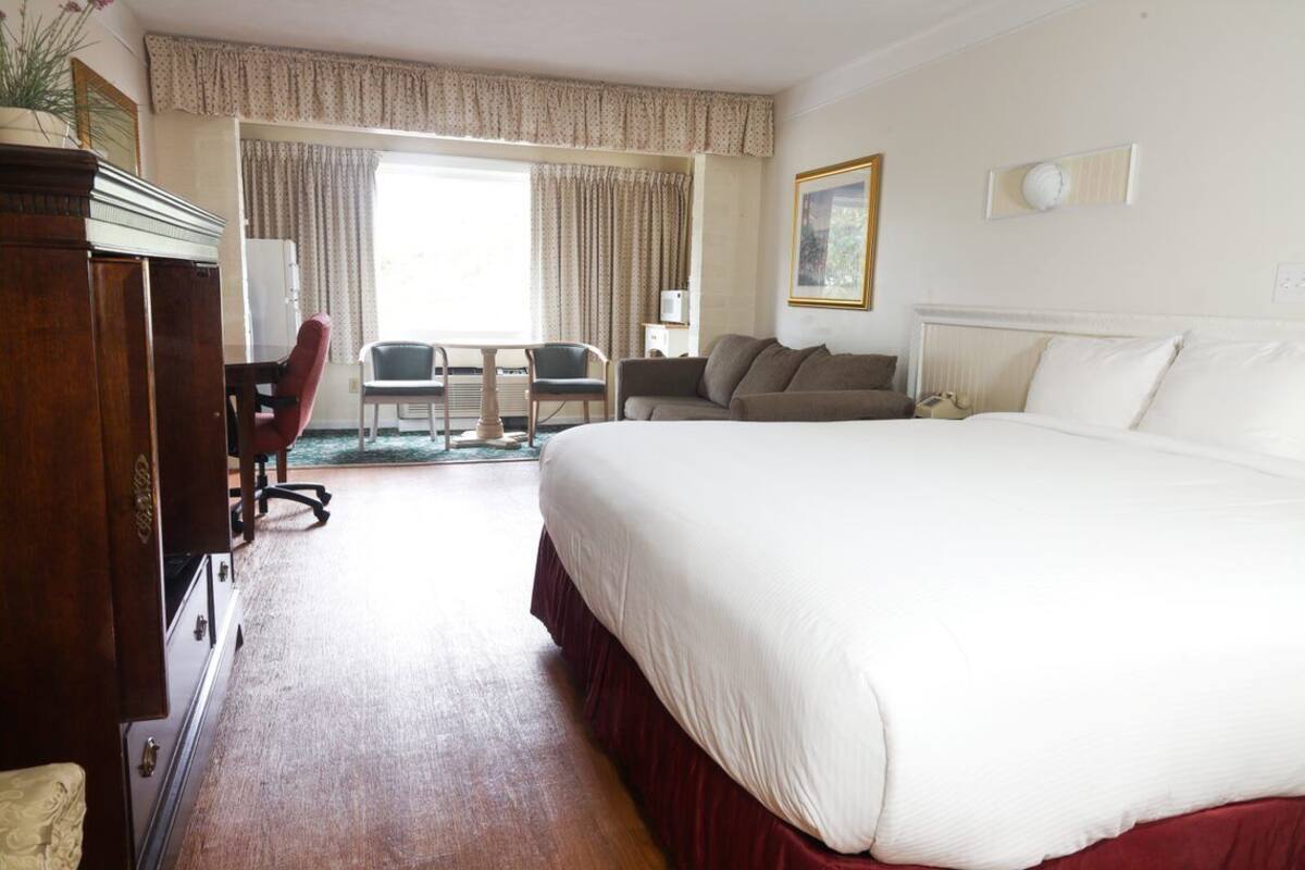 Una habitación de hotel con una cama grande, un escritorio con silla, un sofá y un aparador.