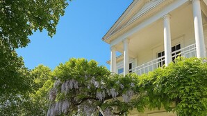 Een wit gebouw met een veranda, een Amerikaanse vlag en het getal '100' op de deur.