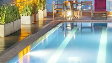 Una piscina al aire libre, sillones reclinables de piscina