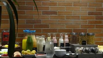 A buffet with various food items and beverages, including fruits, yogurt, and granola.