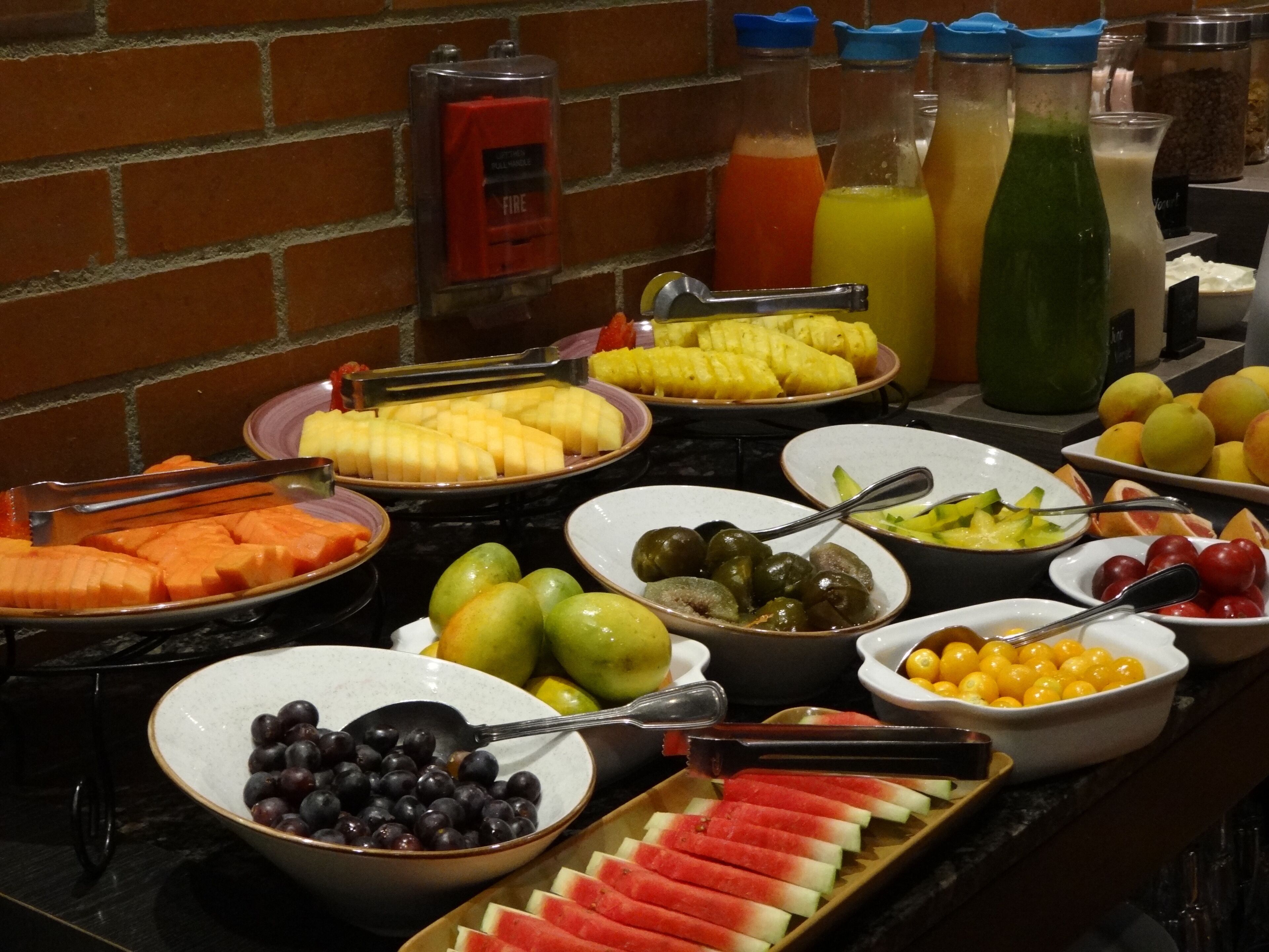 A buffet with various fruits, vegetables, and beverages.