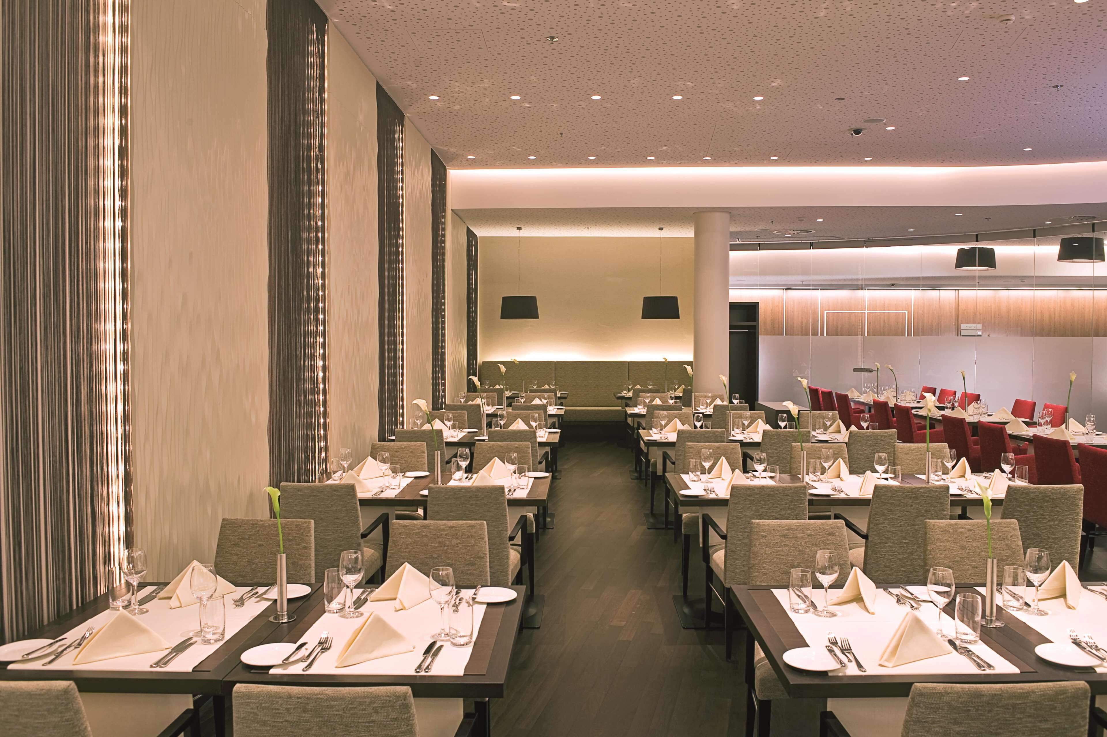 Ein Restaurant mit mehreren Tischen, das zum Essen einlädt, mit modernem Interieur in neutralen Farben und einem klaren Design.