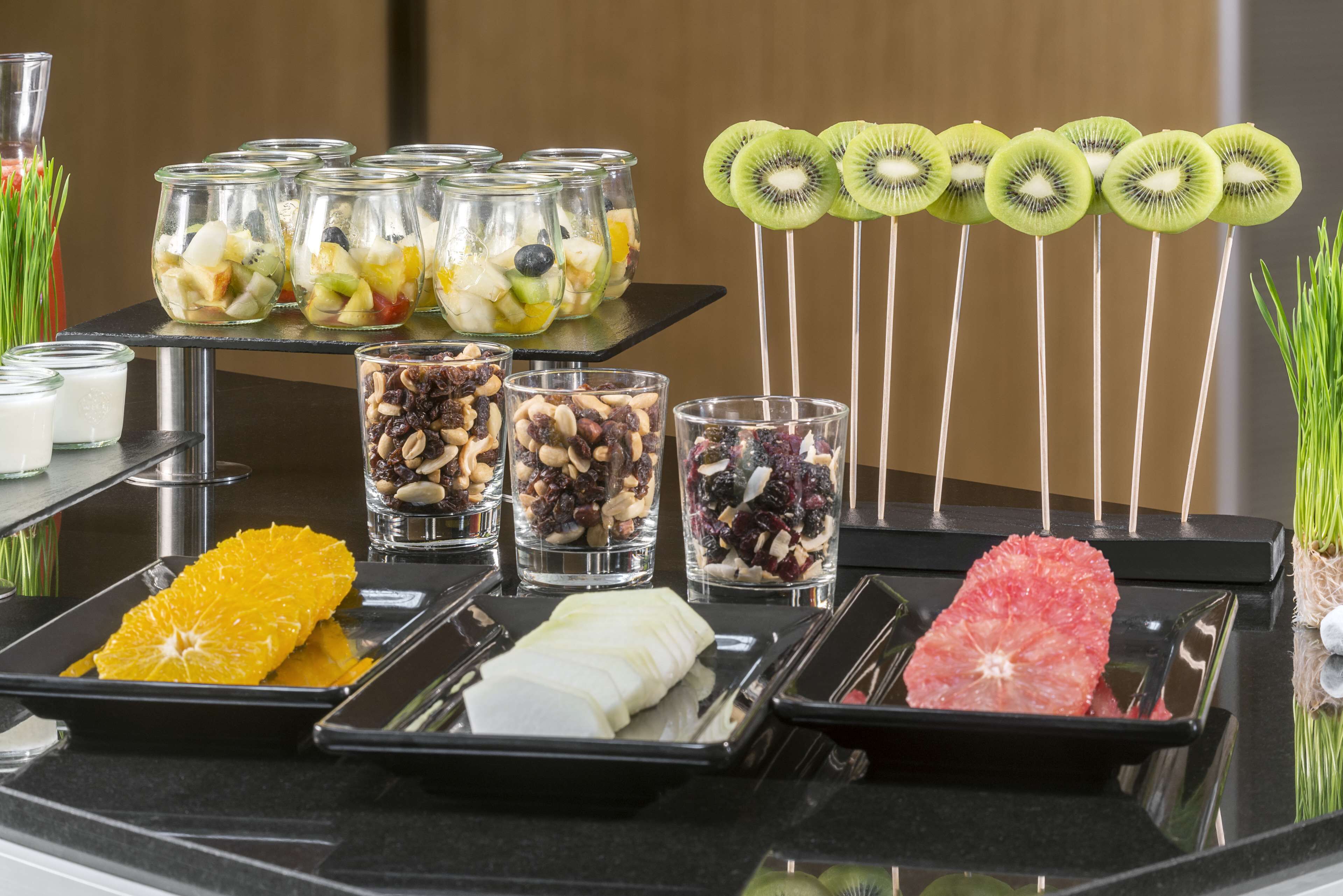 Un bufé con diversos alimentos, entre ellos frutas, nueces y pomelo.