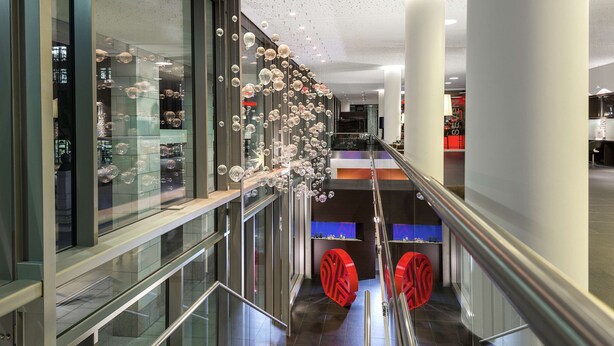 A modern interior with glass railings, a staircase, and a decorative bubble installation. - NH Collection Dresden Altmarkt (Dresden)