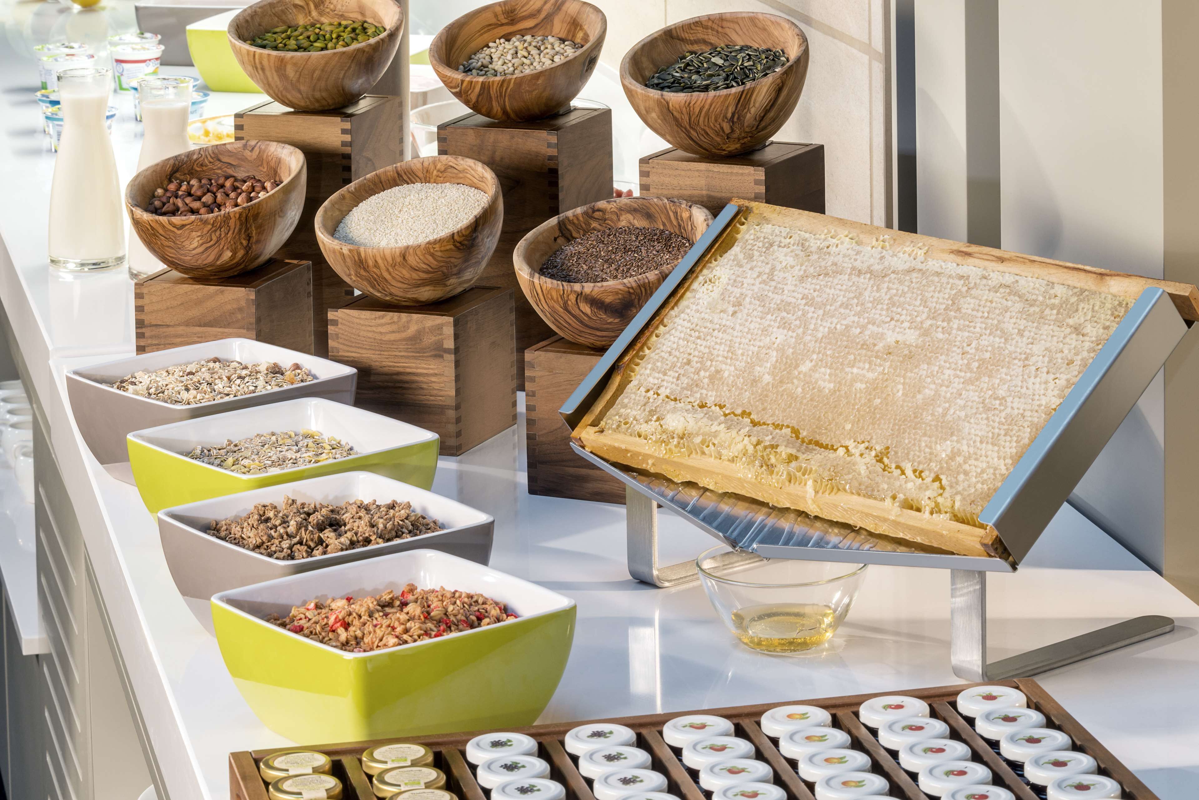 A buffet with various food items in wooden and green bowls, a honeycomb display, and a tray of cookies.