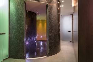 A modern interior with a curved wall featuring mosaic tiles and a reflective floor.