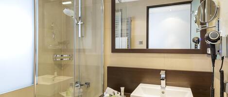 Un baño moderno con cabina de ducha de vidrio, un lavabo blanco y un espejo sobre el lavabo.