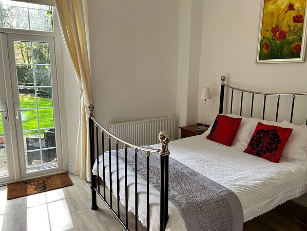 Un dormitorio con cama, mesita de noche, lámpara y ventana con cortinas.
