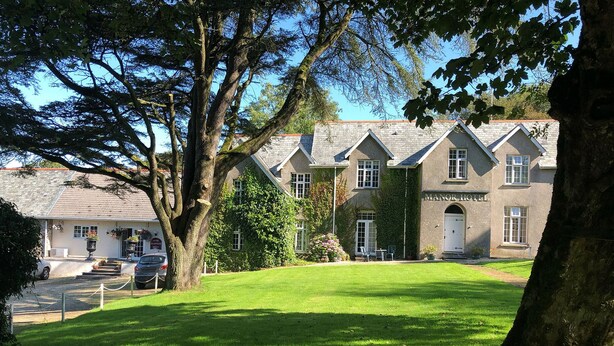 A manor hotel with a stone facade, multiple windows, and a well-maintained lawn. - Exmoor Manor Guest House (Lynton)