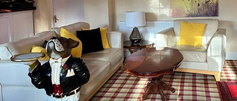 A living room with a checkered floor, a white sofa, a wooden coffee table, and a decorative dog statue.