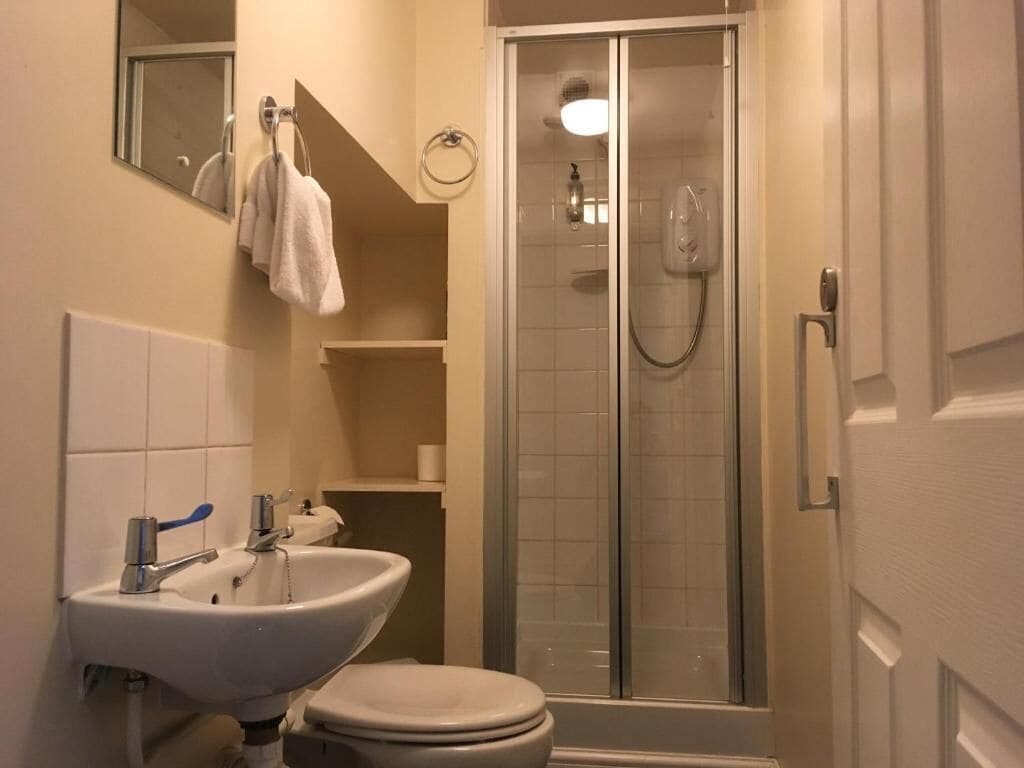 Une salle de bain équipée d’un lavabo, de toilettes et d’une douche à parois de verre.