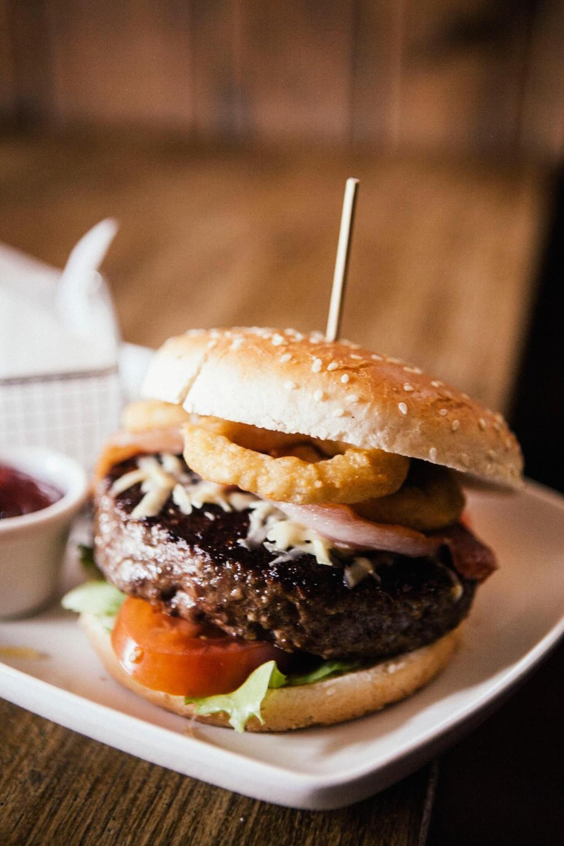 Hamburguesa con pan de sésamo, lechuga, tomate, queso y una hamburguesa de carne, servida en un plato blanco.