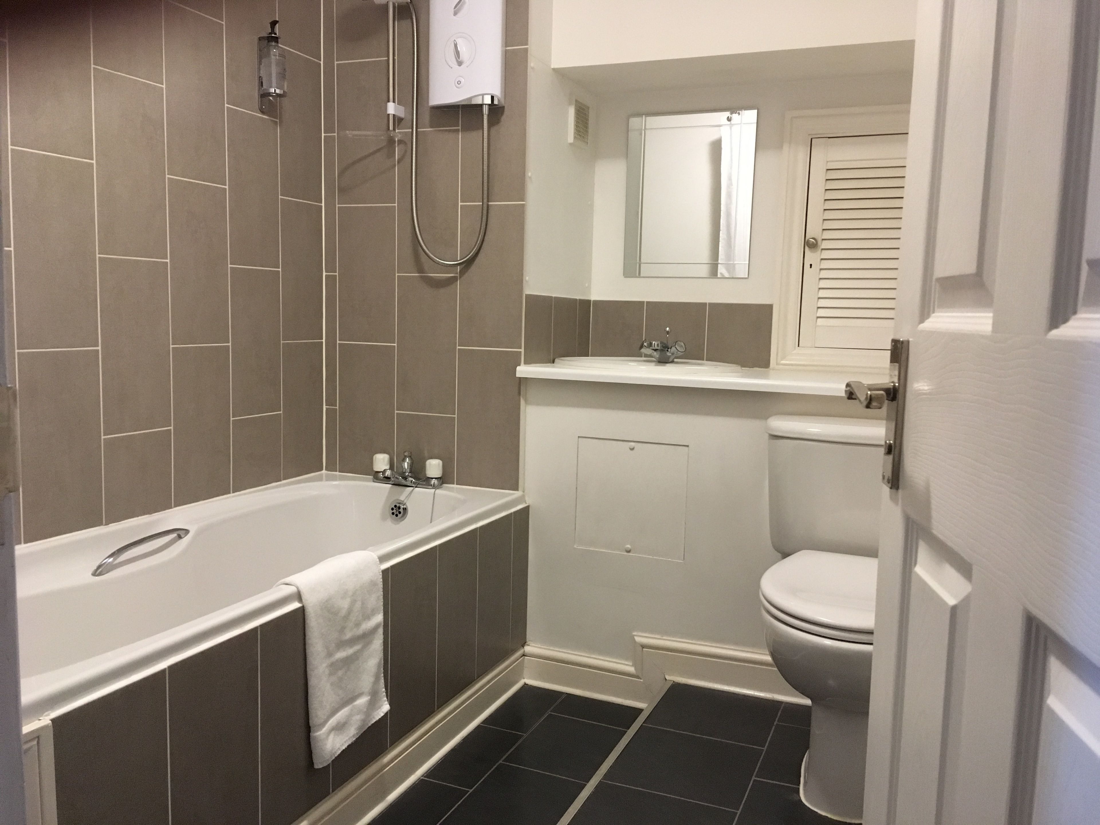 A bathroom with a bathtub, toilet, and a showerhead.