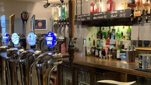 A bar area with multiple beer taps, a Guinness tap, and various bottles and glasses on shelves. - The Silverton Inn - B&B (Exeter)