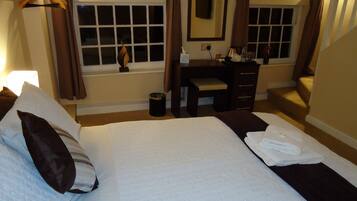 A hotel room with two beds, a desk, a chair, a mirror, and a window with curtains.