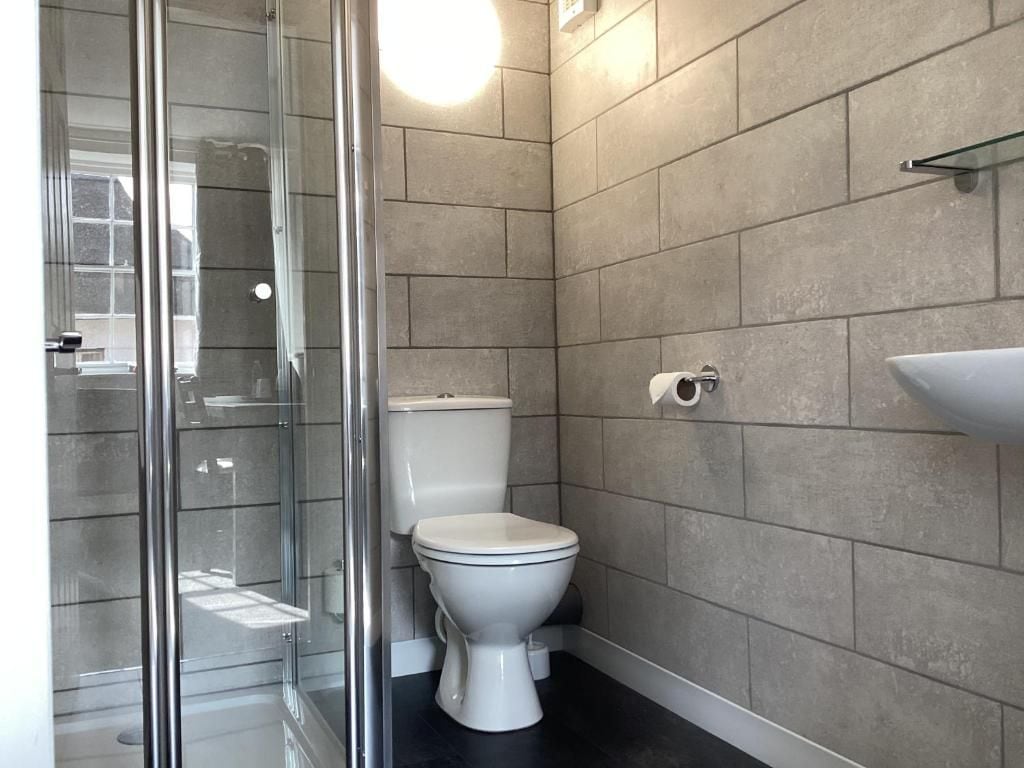 Un bagno moderno con cabina doccia in vetro, un water bianco e un lavabo sospeso.