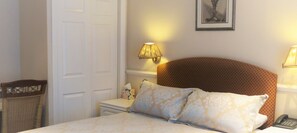 Un lit bien fait, avec des oreillers, une lampe de chevet, une petite table sur laquelle se trouve une boîte de mouchoirs et un téléphone.