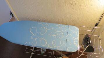 An ironing board with a blue surface and a wire rack holding an iron.