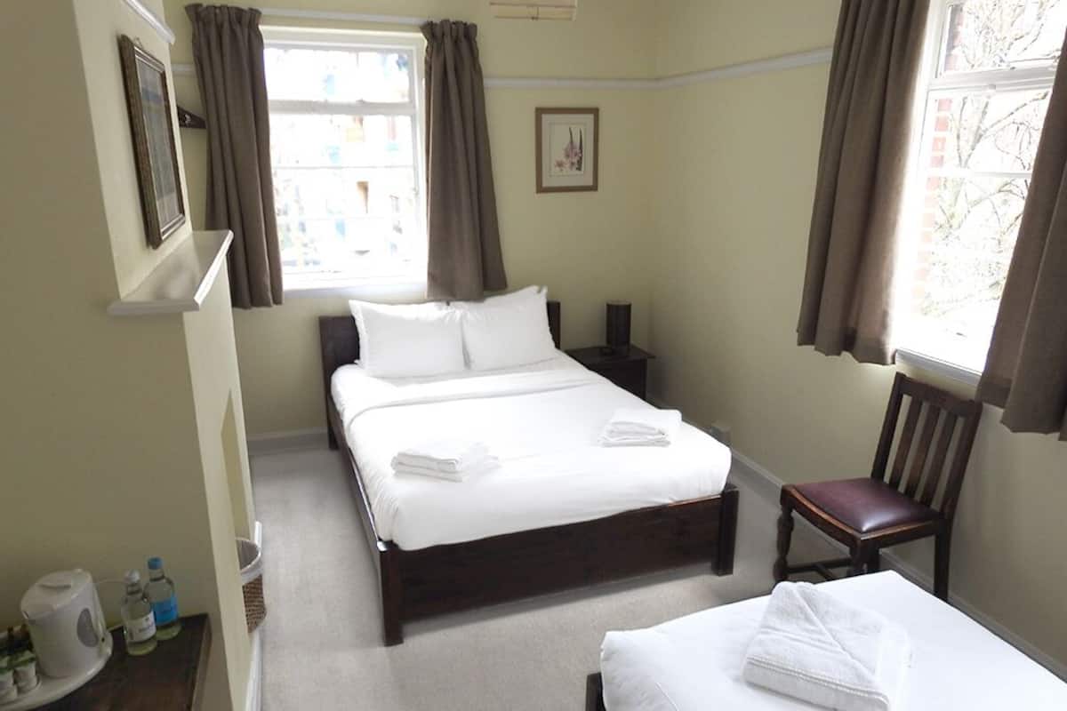 Una habitación de hotel con una cama grande, una mesita de noche, una silla y una ventana con cortinas.