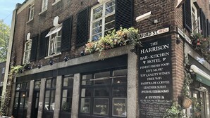 Un edificio de ladrillo con mesas al aire libre y un cartel que anuncia The Harrison Bar, Kitchen & Hotel.