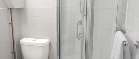 A modern bathroom with a toilet, a glass-enclosed shower, and a towel rack.