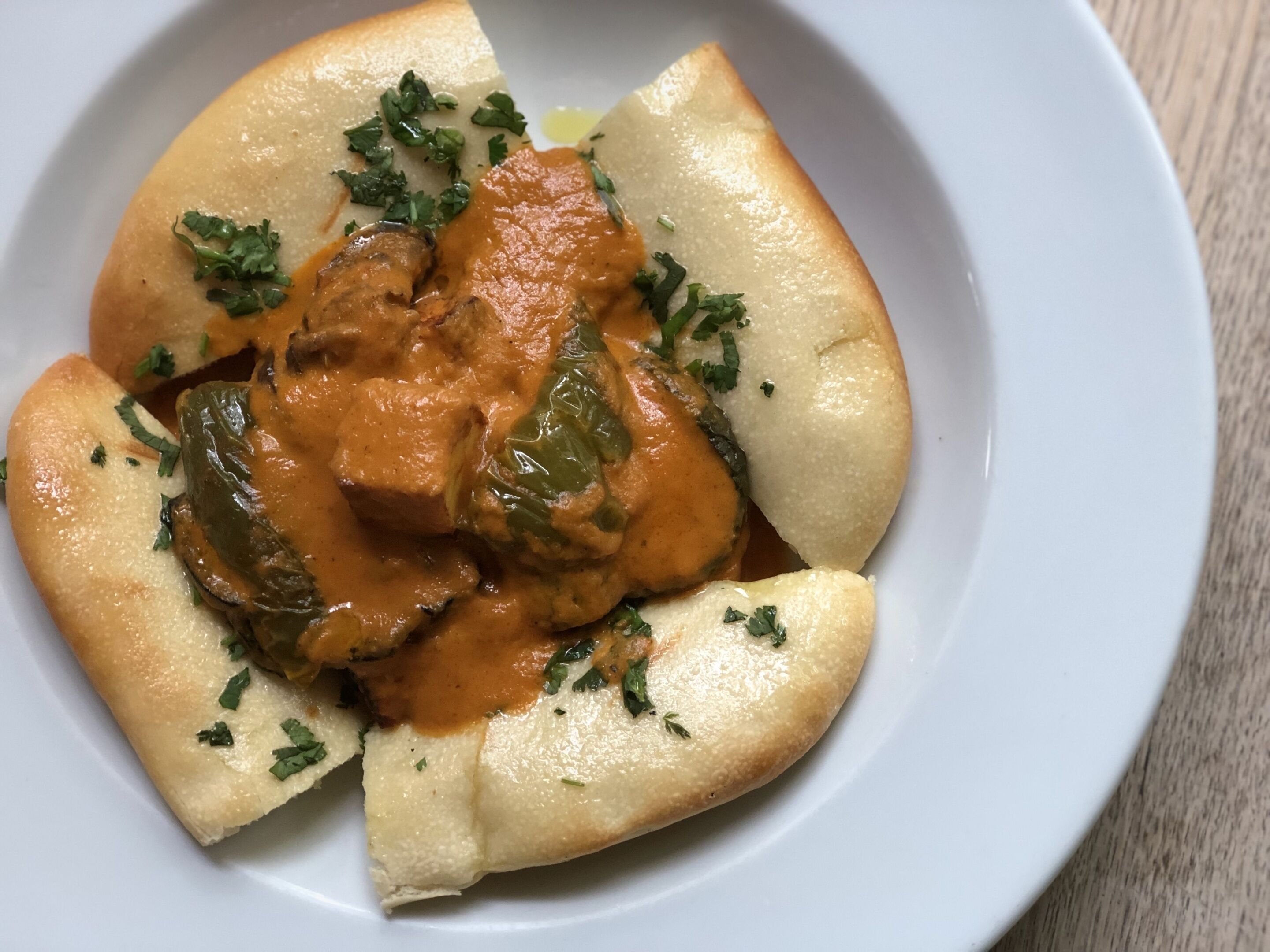 A plate of food with a creamy sauce, green vegetables, and herbs.