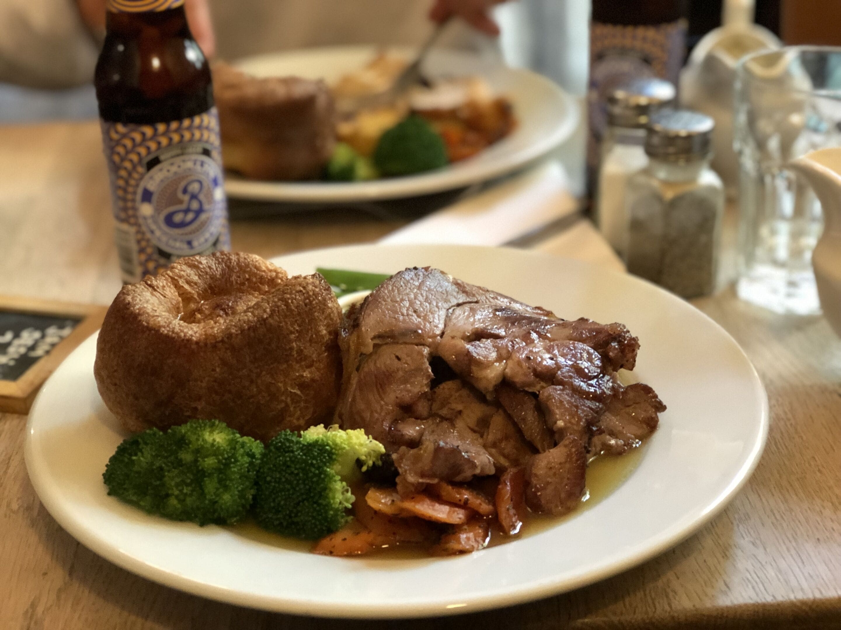Een bord met rundvlees, groenten en een Yorkshire pudding.
