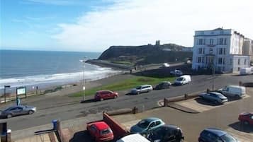 Un estacionamiento con coches, un edificio y vistas a la playa y el océano.