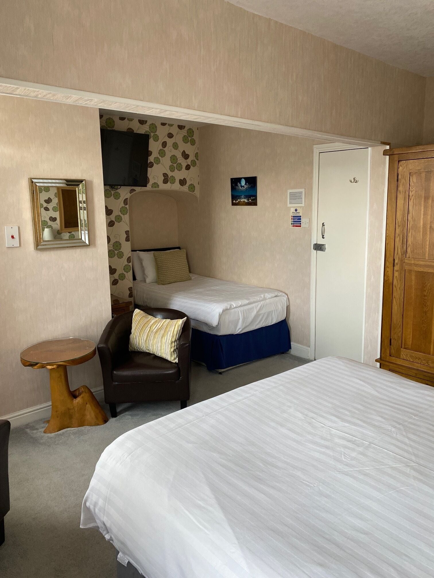 A bedroom with a single bed, a chair, a small table, and a wardrobe.