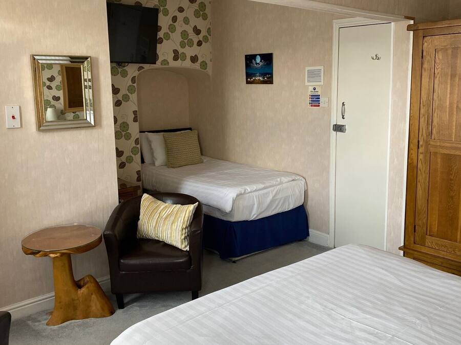 A bedroom with a single bed, a chair, a small table, and a wardrobe.