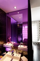 Une salle de bain moderne avec un grand miroir, un lavabo et un espace douche.