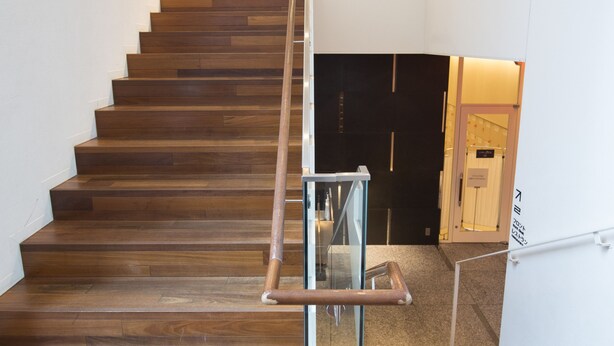 Una escalera de madera con barandilla de vidrio que sube a un piso superior.