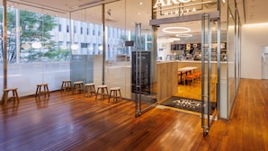 A modern cafe with a glass facade, wooden flooring, and a visible seating area with stools.