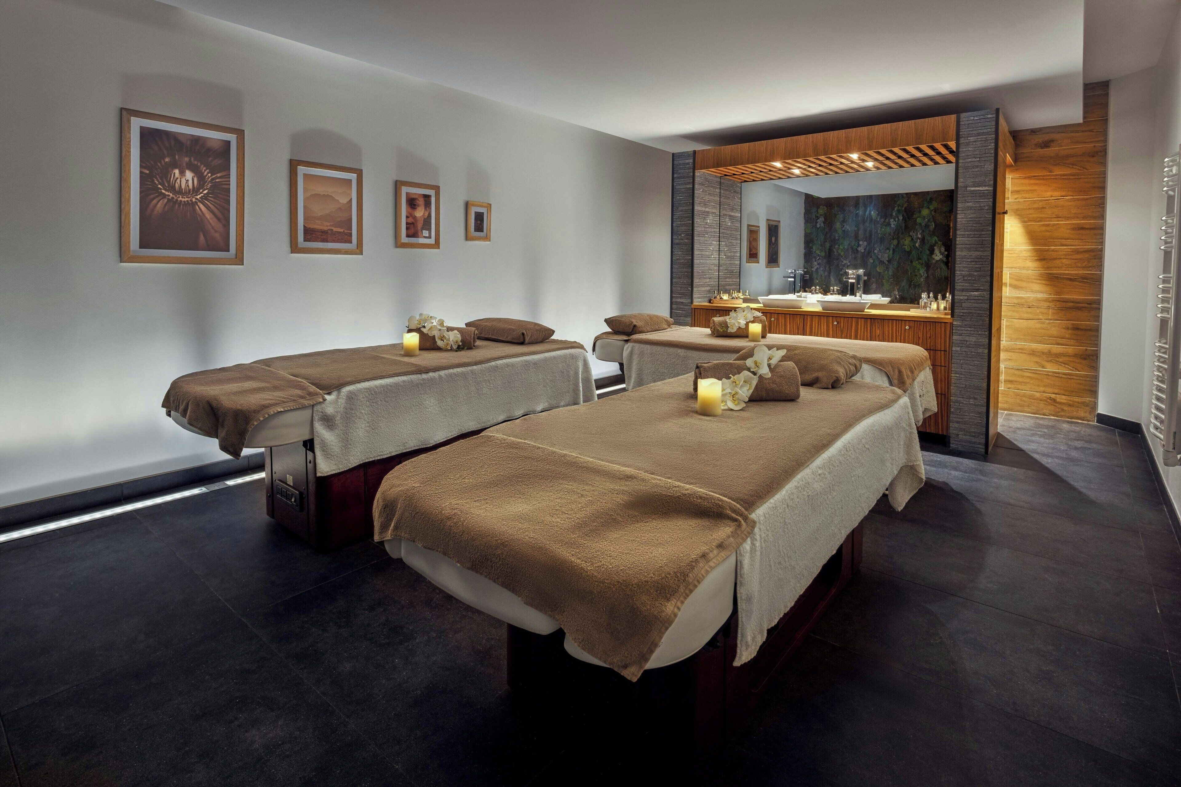 A spa room with two beds, a mirror, and a wooden cabinet.