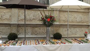 A buffet table with various food items and a decorative vase with flowers.