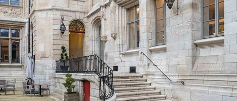 A historic building with a stone facade, a red door, and a staircase leading to an upper level.