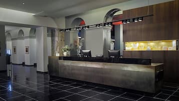 Un espace d’accueil moderne avec un sol carrelé noir poli, un comptoir d’accueil et un présentoir de produits de toilette.