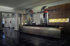Een moderne receptie met een glanzende zwarte tegelvloer, een receptiebalie en een presentatie van toiletartikelen.