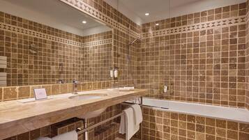 A bathroom with a large mirror, a sink, a bathtub, and tiled walls.
