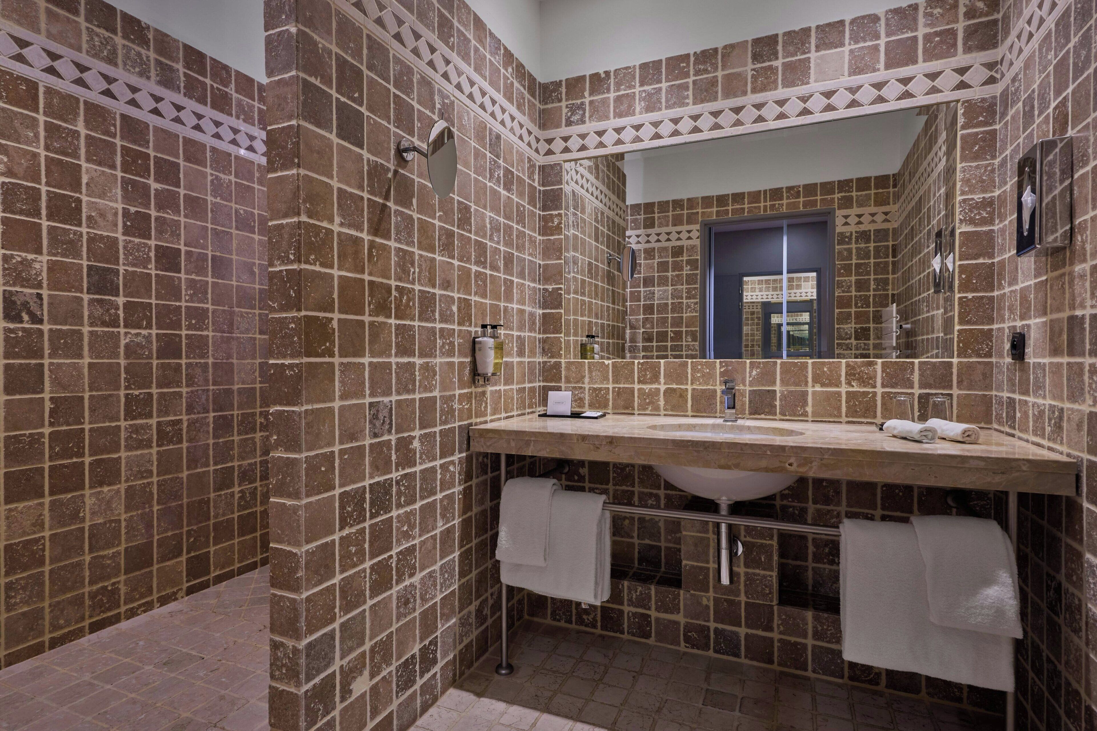 A bathroom with a large mirror, a sink, and two towels hanging on a rack.
