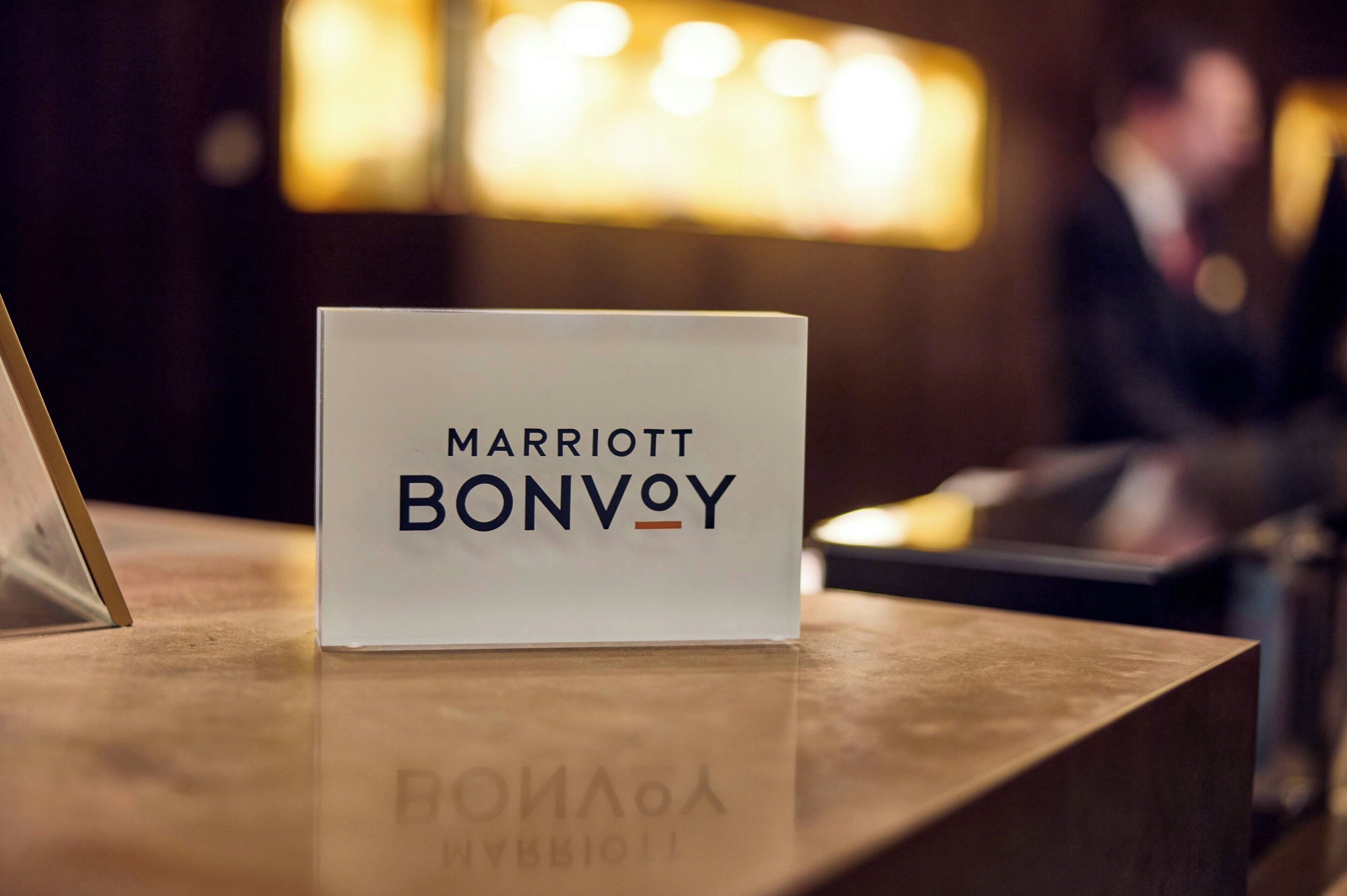 Een bord met de tekst 'MARRIOTT BONVOY' op een houten receptiebalie.