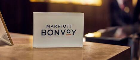 Een bord met de tekst 'MARRIOTT BONVOY' op een houten receptiebalie.