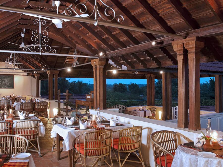 A restaurant with wooden beams and tables set for dining, overlooking a scenic view.