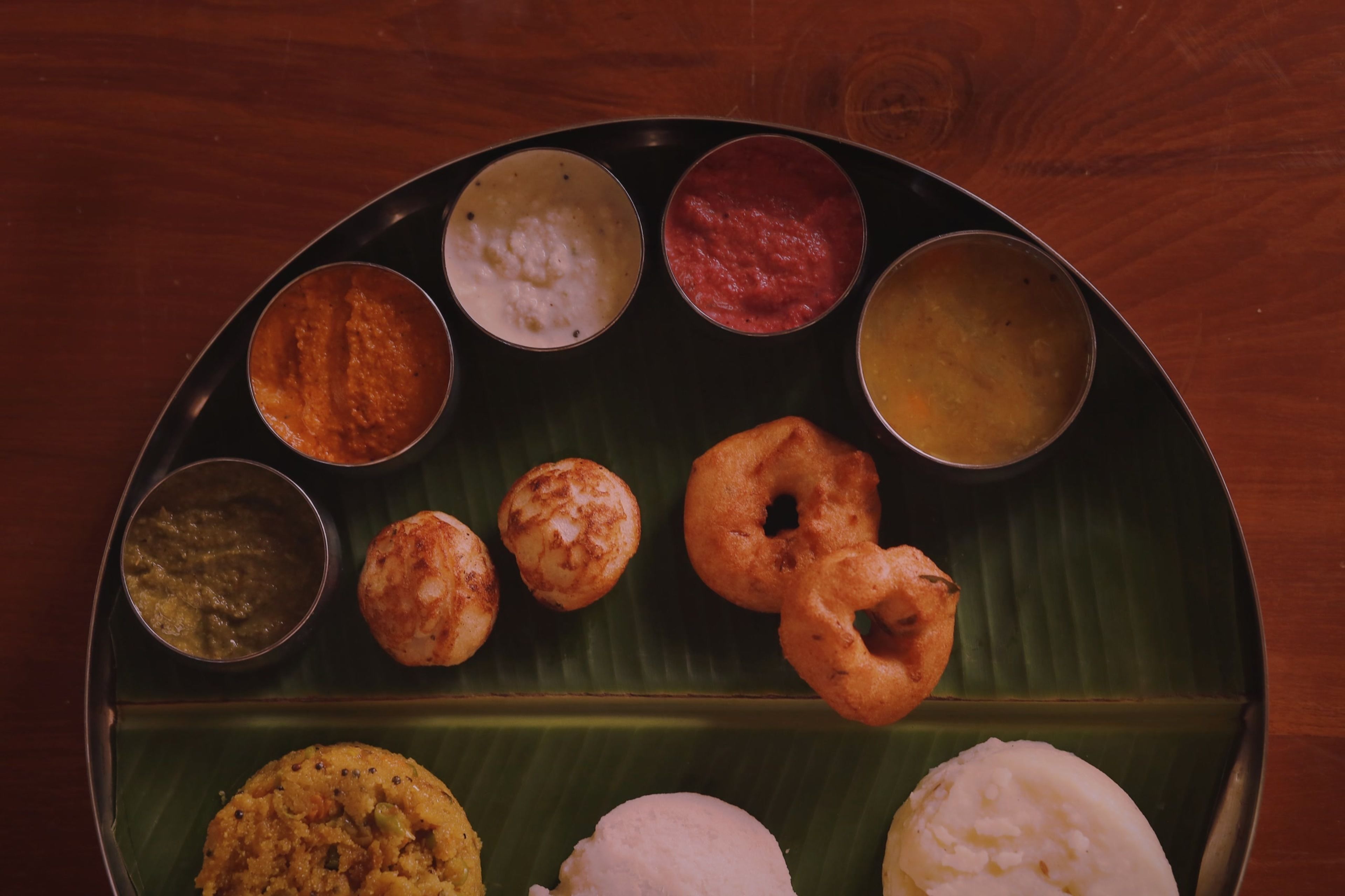 A traditional South Indian meal served on a banana leaf with various dishes including idlis, dosas, and chutneys.
