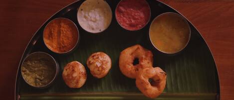 A traditional South Indian meal served on a banana leaf with various dishes including idlis, dosas, and chutneys.